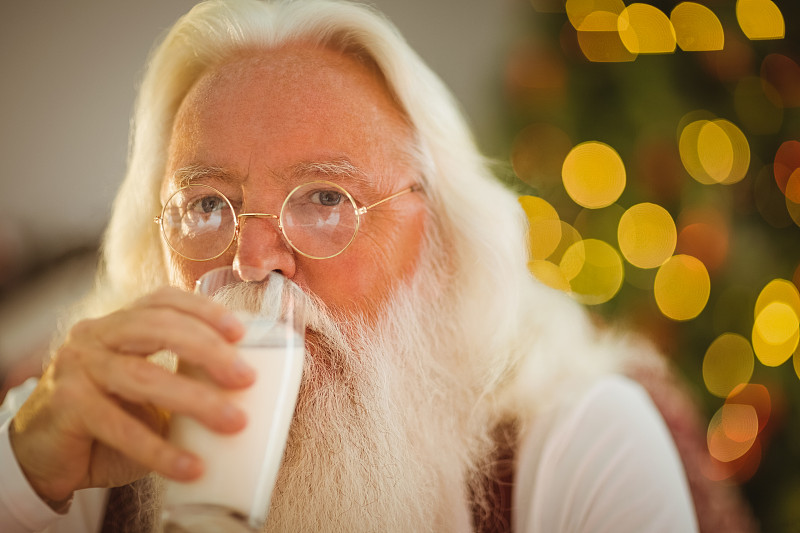 圣诞老人在家里的客厅里喝着一杯牛奶图片下载