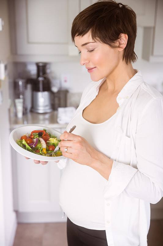 孕妇在家厨房里吃着一碗沙拉图片素材
