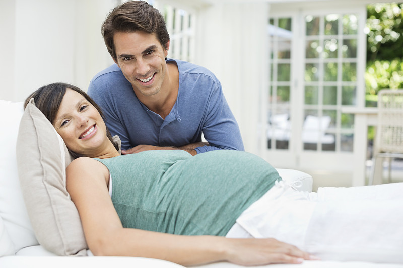 一个男人坐在躺在床上的孕妇旁边图片素材