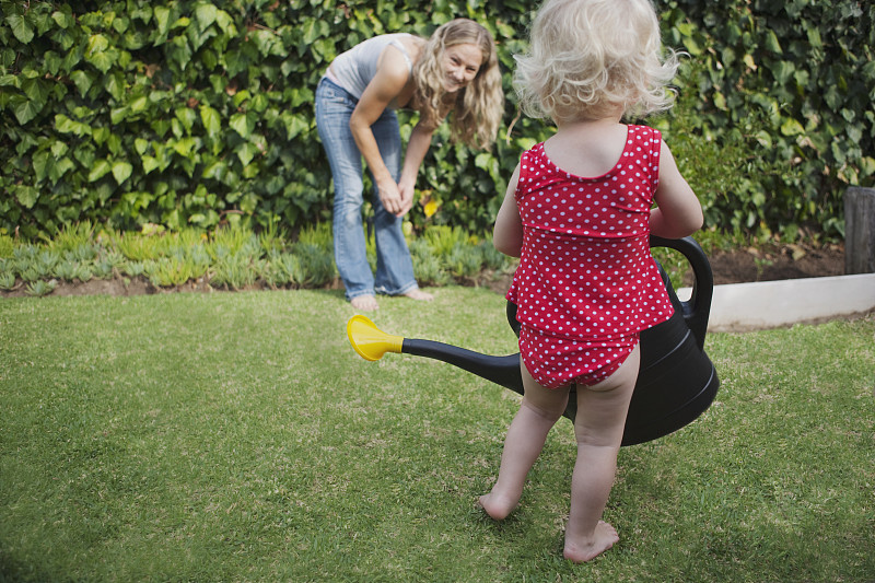 母亲带着女儿(1-2)在菜园里，女孩正拿着喷壶图片下载