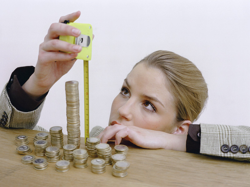 女人用卷尺蹲在欧元硬币前图片下载