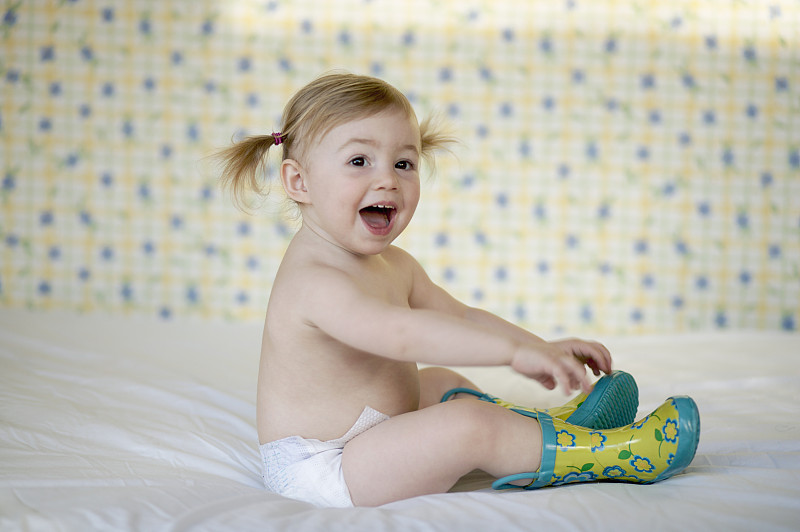 穿着纸尿裤和胶鞋的微笑女婴图片素材