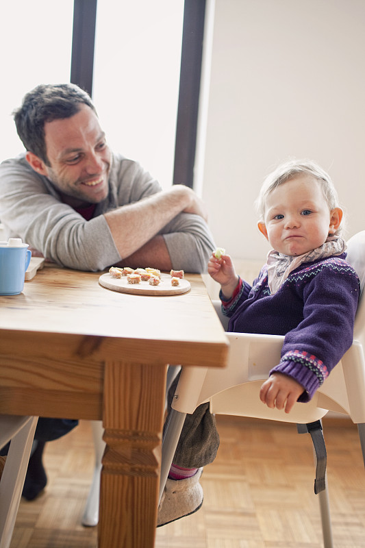 父亲和女儿(6-12个月)坐在餐桌旁图片下载