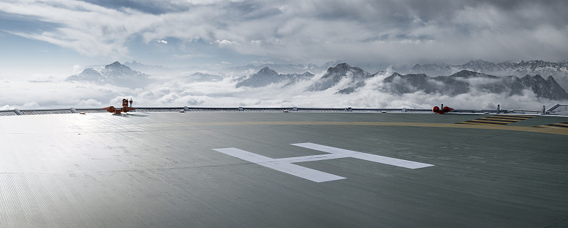 雪山云海背景的逆光下的直升机停机坪图片素材