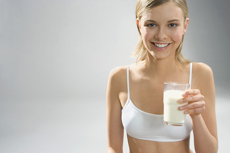 年轻女子嘴里围着牛奶，手里拿着一杯牛奶图片下载