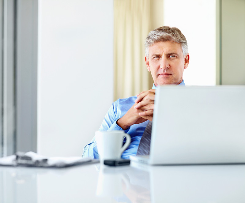 一个成熟的商人坐在电脑前工作图片下载