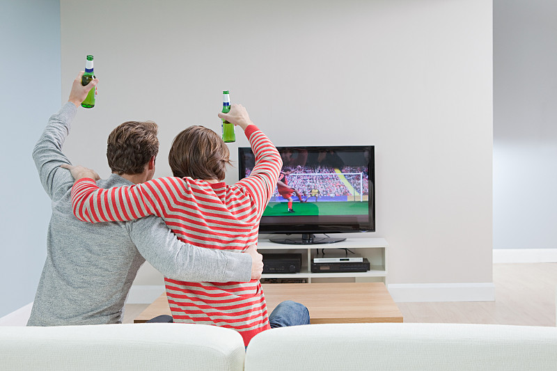 两个年轻人在电视上看足球比赛图片下载