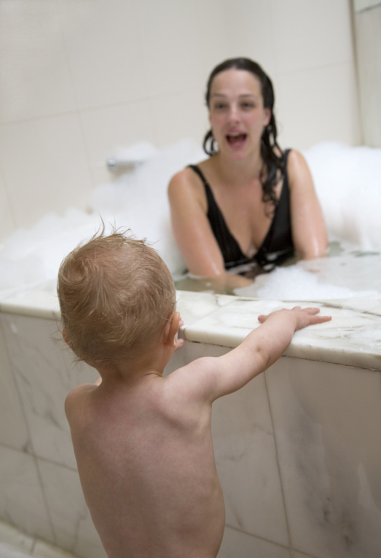 妈妈在泡泡温泉浴和婴儿看着图片下载
