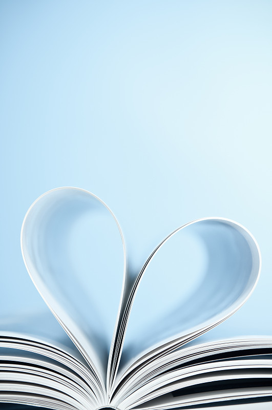 爱读书的人，把书页折叠成心形，蓝色的背景图片下载