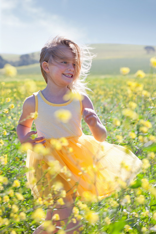 Smiling girl playing in field of flowers图片素材