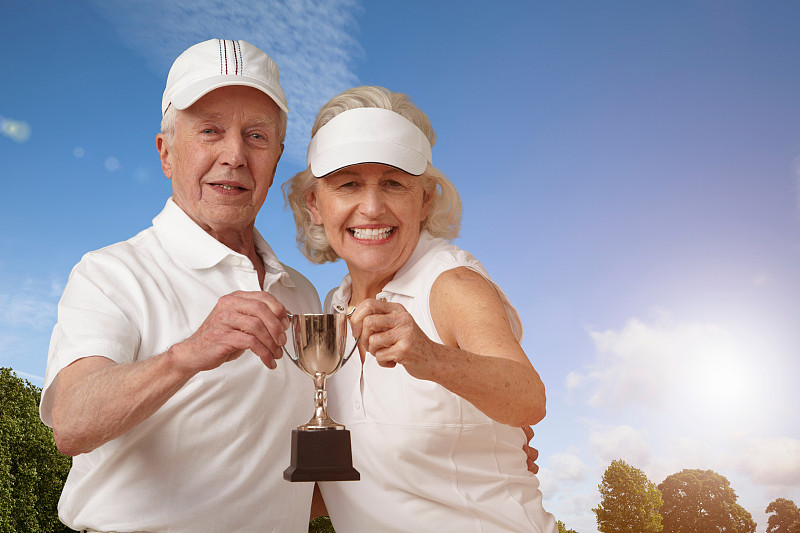 一对老年夫妇拿着网球奖杯图片下载