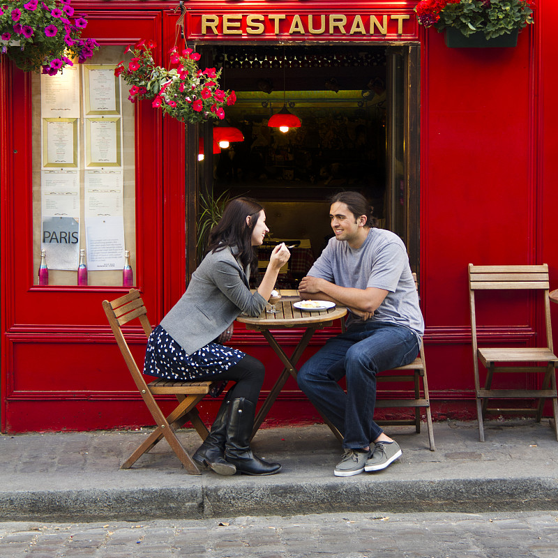 法国，巴黎，一对年轻夫妇坐在路边咖啡馆里图片下载