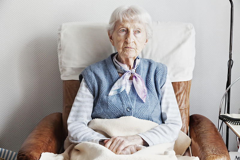 坐在扶手椅上的老妇人忧心忡忡图片下载