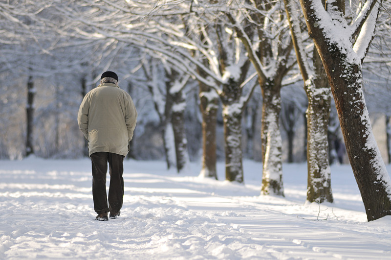 老人在白雪覆盖的公园里散步图片素材