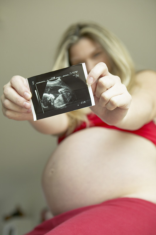 年轻孕妇抱着超声波，低角度观察图片下载