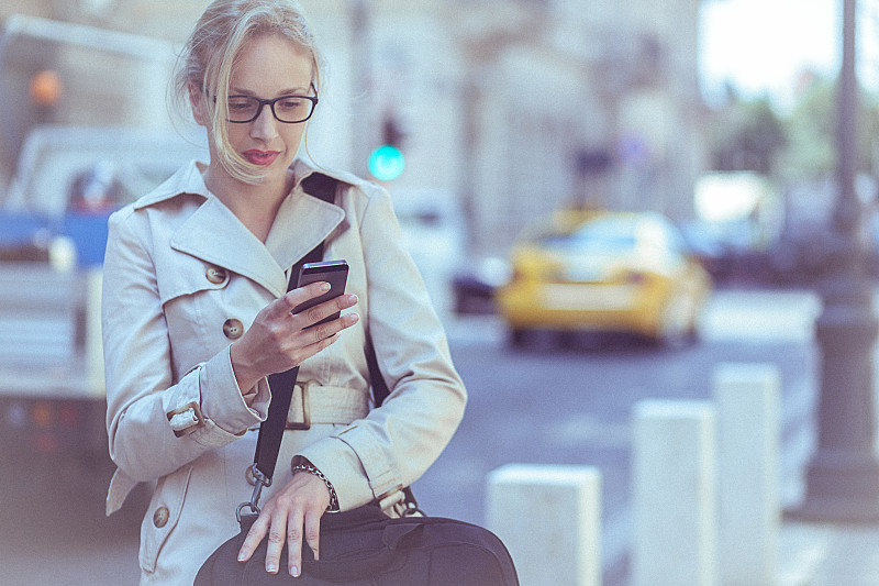 年轻的女商人在城市环境中使用手机图片下载
