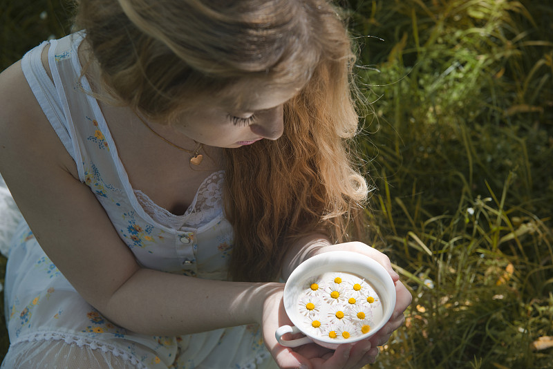 小女孩捧着盛满雏菊的牛奶碗图片下载