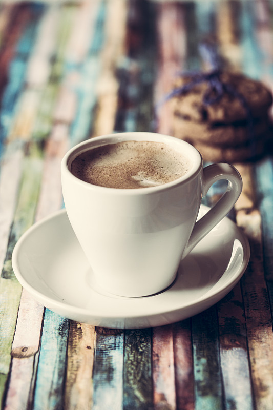 一杯咖啡和彩色木头上的巧克力饼干图片素材
