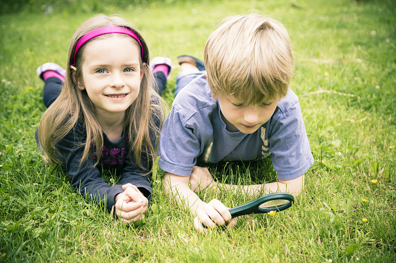 哥哥和妹妹躺在草地上用放大镜看花图片下载