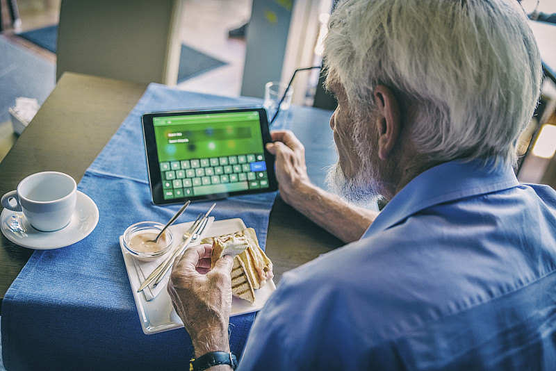 老人们吃着早餐，用着平板电脑。图片下载
