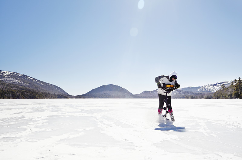 阿卡迪亚，一名女子在结冰的湖面上练习冰上钓鱼图片下载