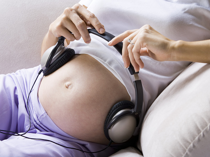 一名孕妇腹部戴着耳机的剖面图图片下载