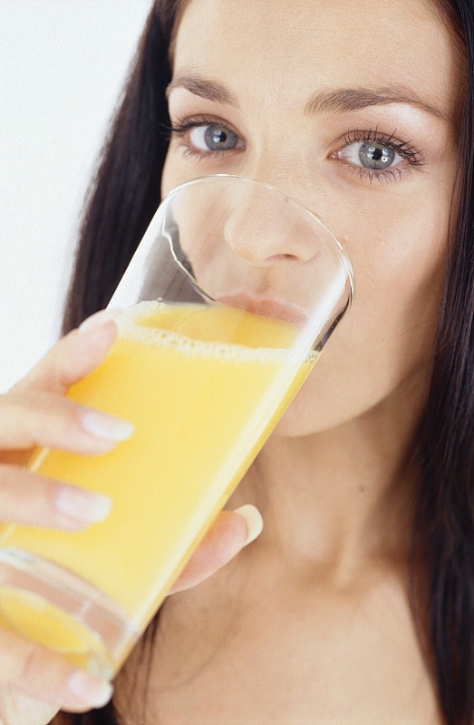 Woman drinking glass of orange juice图片素材