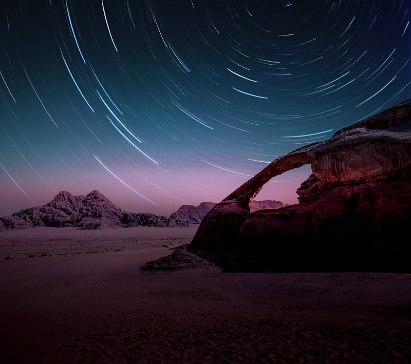 长时间曝光的明星在约旦的瓦迪拉姆沙漠与自然拱门。图片下载