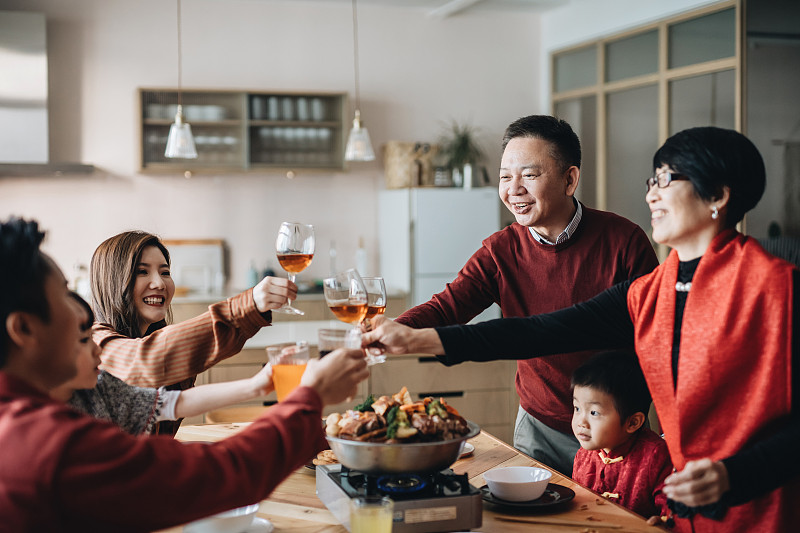三代快乐的亚洲家庭庆祝中国新年，一边品尝传统的中国菜，一边品尝团圆饭图片下载