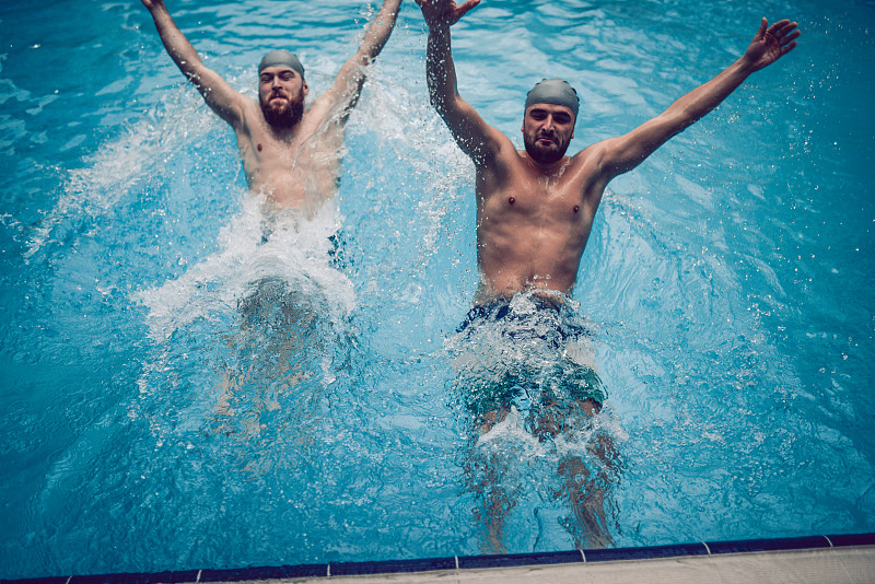 快乐的男性在游泳池里跳跃和玩耍图片素材
