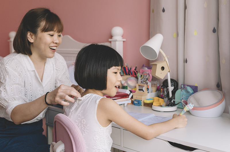 一位亚洲华人母亲在周末的闲暇时间和女儿一起做作业图片素材