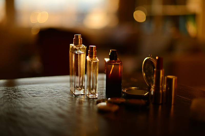 香水瓶，项链和化妆品在美丽的金色阳光下的黑色背景图片下载