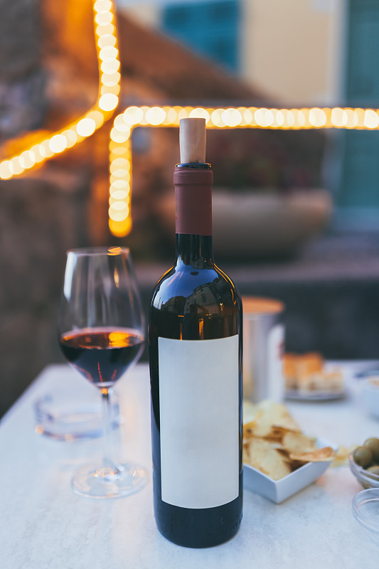 桌上放着一瓶红酒和一只玻璃杯，薯条，橄榄，餐厅里就有。柔和的色彩，夏天，意大利。为文本复制空间。意大利利古里亚省特拉罗。图片素材