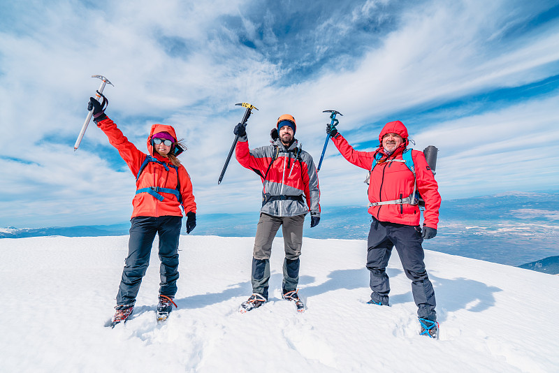 冬季，高山登山队正手持冰镐站在高海拔的山峰上图片下载