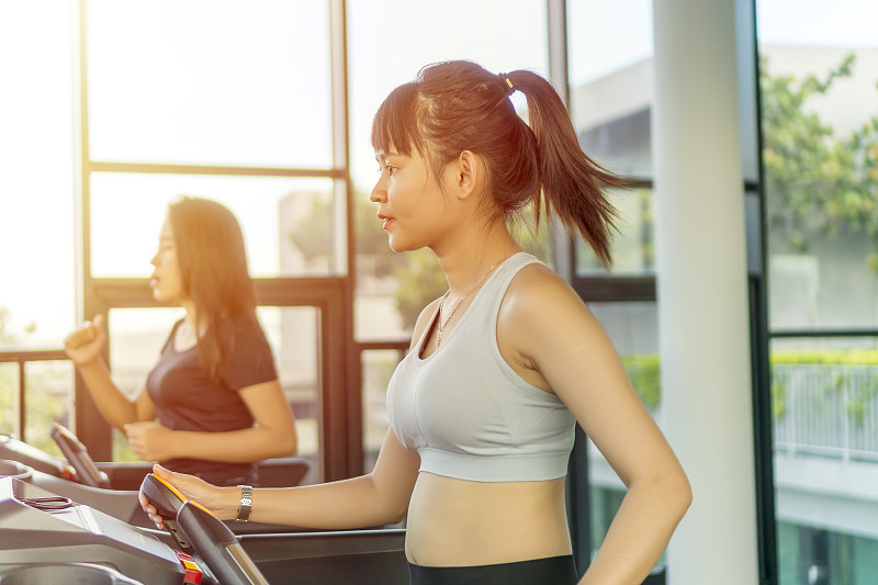 女性在健身房跑步机上锻炼的侧面图图片素材