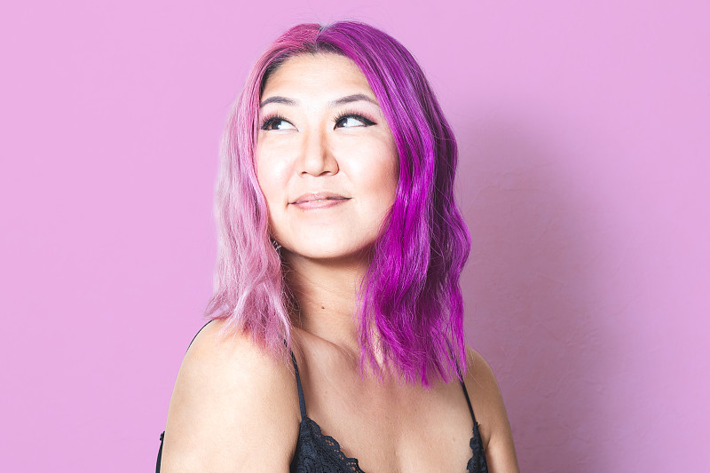 粉色和紫色的头发映衬着相配的粉色背景图片下载