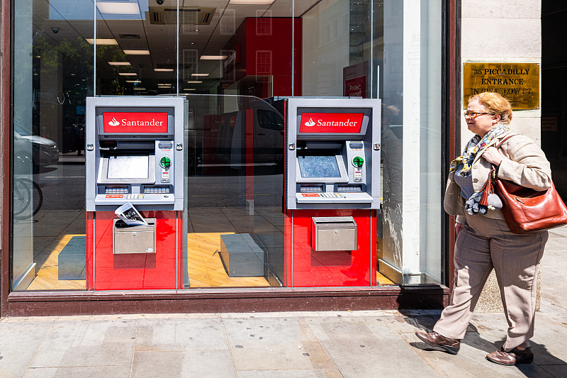 红色的桑坦德银行现金标志atm与行人在银行分行办公大楼图片下载