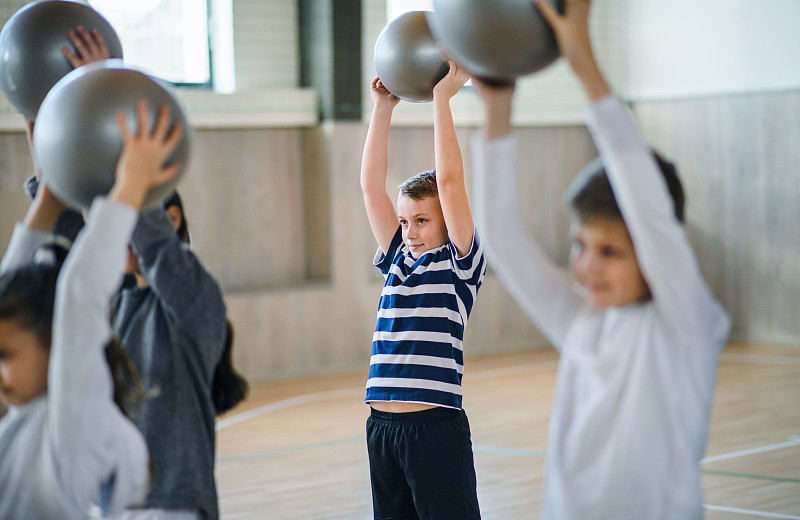 一组学生在体育课上用球在室内运动。图片素材