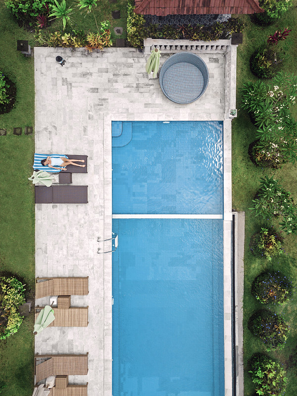 鸟瞰图迷人的女人附近的游泳池在度假村图片下载