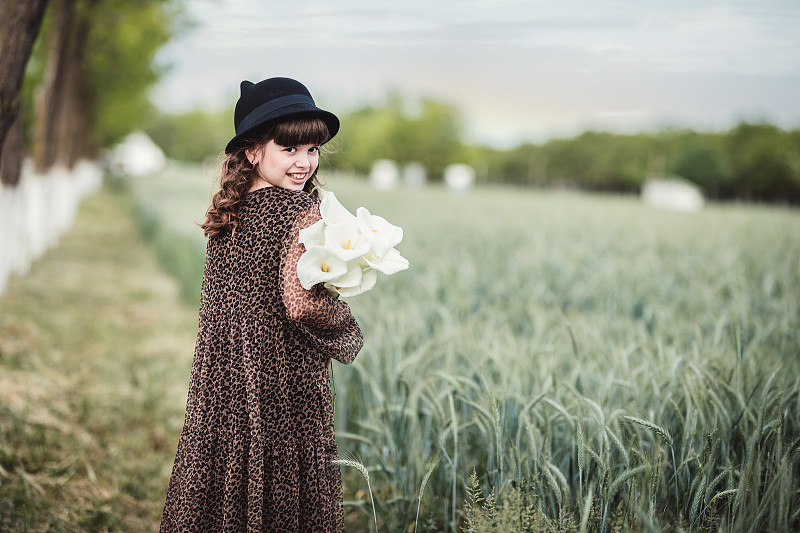 美丽的女孩在她的肩膀微笑，当走在她的鲜花在她的臂弯图片下载