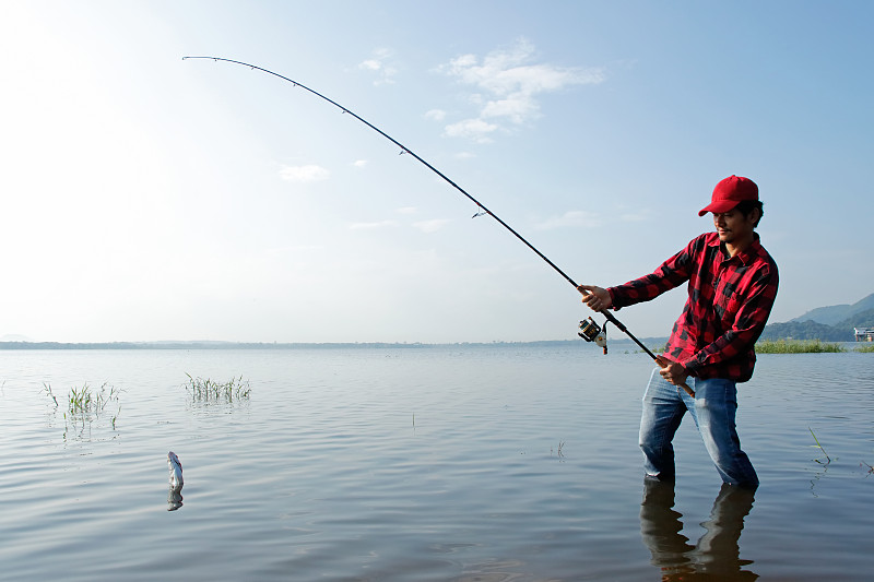 渔夫站在湖里，用钓竿钓鱼图片下载