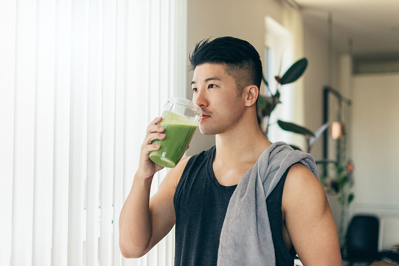 自信的亚洲男人在锻炼后喝蛋白质奶昔图片素材