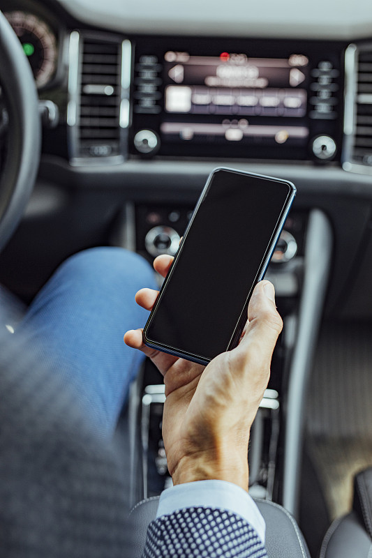 汽车里的科技:一个商人坐在驾驶座上发短信(空白屏幕，拷贝空间)图片下载