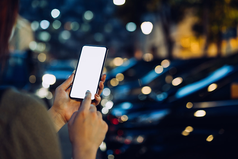 这张照片拍摄的是一位女士在城市的停车场用智能手机走到她的车旁时的手摄影图片下载