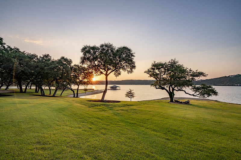 日出的光芒穿过湖泊和草坪穿过树林图片素材