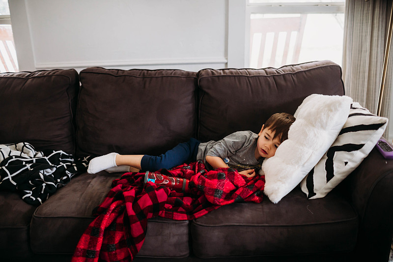 小男孩得了流感，躺在客厅的沙发上图片素材