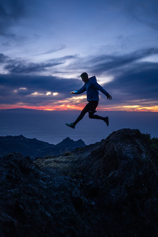 西班牙加那利群岛，戈梅拉岛，一名男子正从岩脊上跳下来图片下载