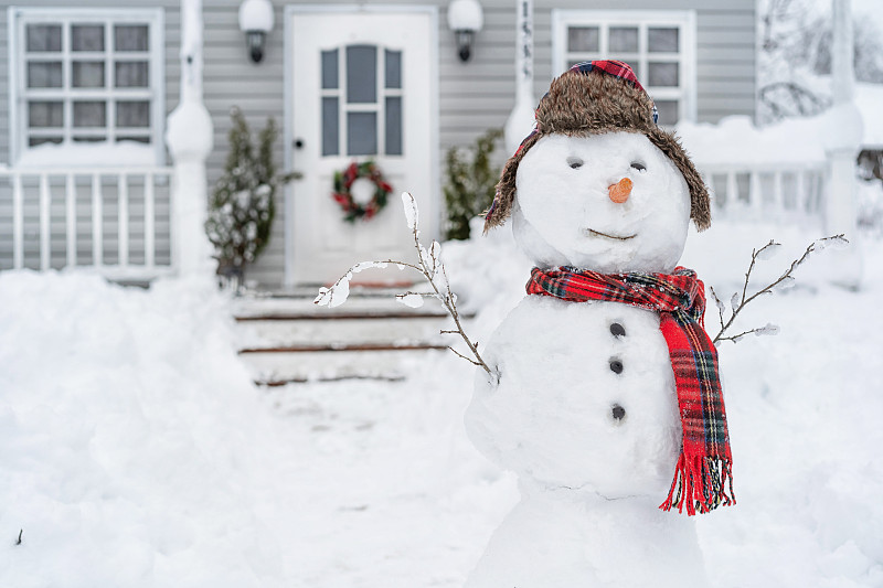 在冬天的一天，雪人在房子前面微笑图片素材