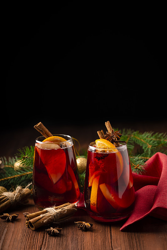 两杯圣诞热红酒装饰，橘子，肉桂和杉树在木制的背景图片下载