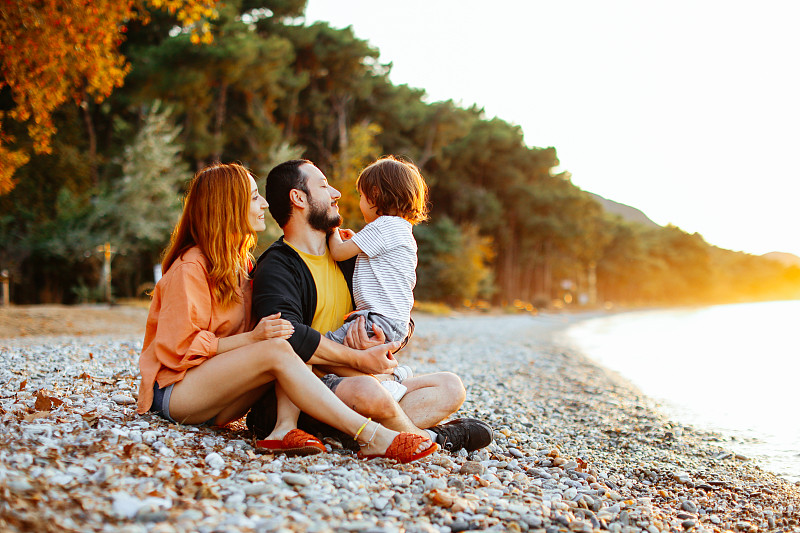 在美丽的夏日，幸福的一家人坐在沙滩上放松图片下载